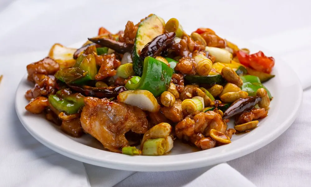Kung pao chicken stir-fry with peanuts, zucchini, scallions and chili on white ceramic plate at 88Baobao, a Chinese restaurant in Lubbock.