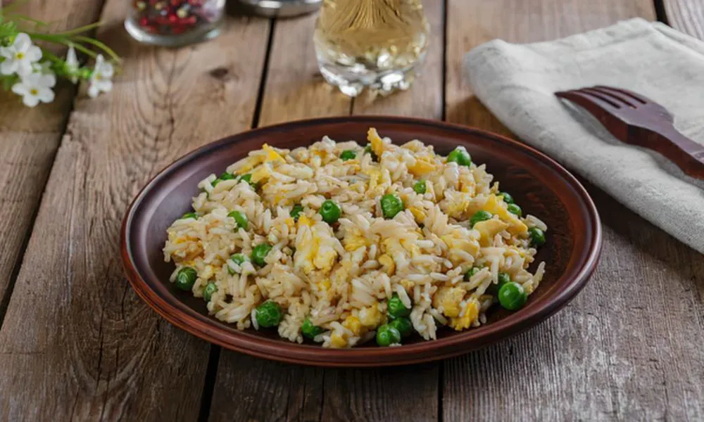 Classic egg fried rice with green peas and scrambled egg on dark brown ceramic plate at 88Baobao, a Chinese restaurant in Lubbock.
