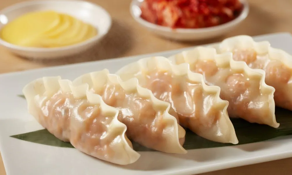 Translucent pan-fried shrimp dumplings lined on green leaf atop rectangular white plate at 88Baobao, a Chinese restaurant in Lubbock.