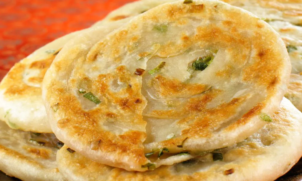 Stacked golden crispy scallion pancakes with layered flaky dough and green onion bits at 88Baobao, a Chinese restaurant in Lubbock.
